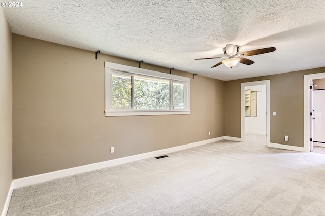 carpeted spare room featuring ceiling fan and a textured ceiling