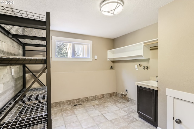 laundry area featuring a textured ceiling, electric dryer hookup, and sink