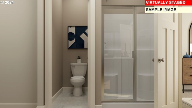 bathroom featuring a shower with door and toilet