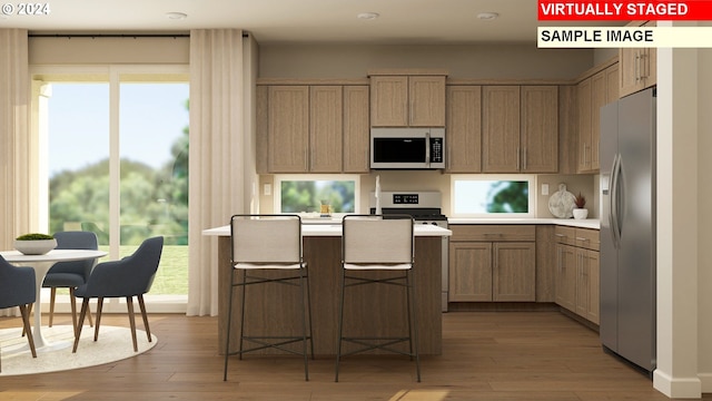 kitchen with a kitchen breakfast bar, appliances with stainless steel finishes, light wood-type flooring, and plenty of natural light