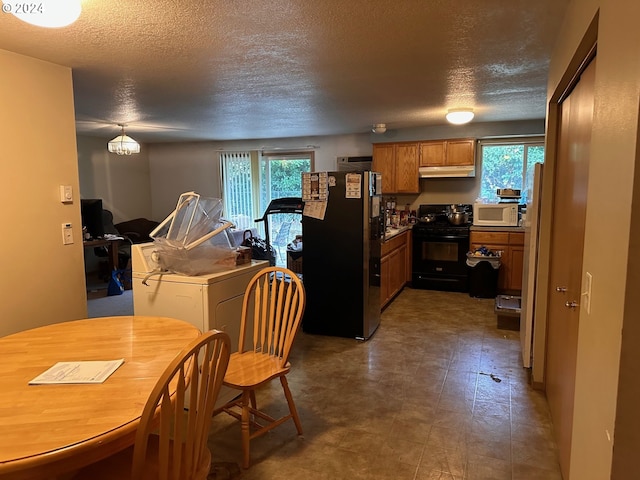 kitchen featuring a textured ceiling, a wealth of natural light, electric range, and stainless steel refrigerator