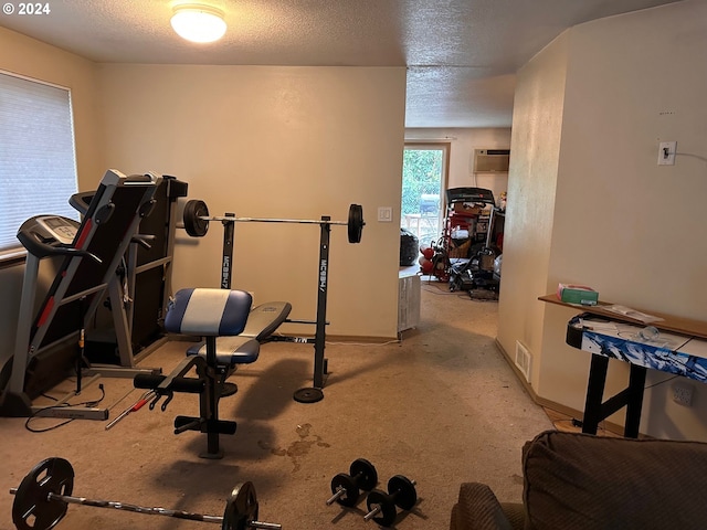 workout area with carpet floors, baseboards, a wall mounted AC, and a textured ceiling