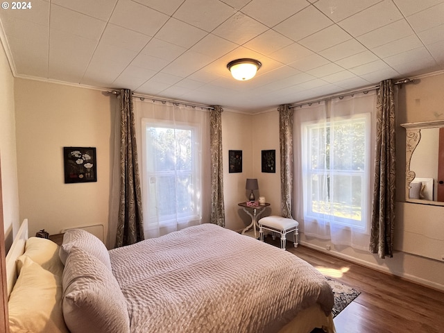 bedroom featuring wood-type flooring, multiple windows, and ornamental molding