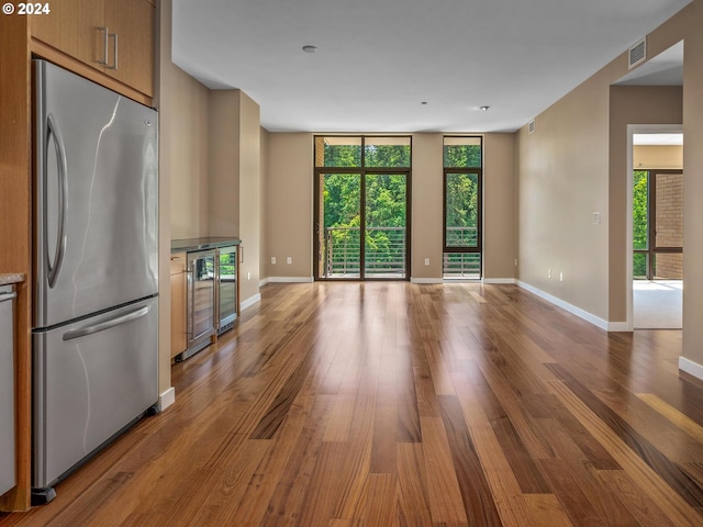 unfurnished living room featuring wine cooler, hardwood / wood-style flooring, and floor to ceiling windows