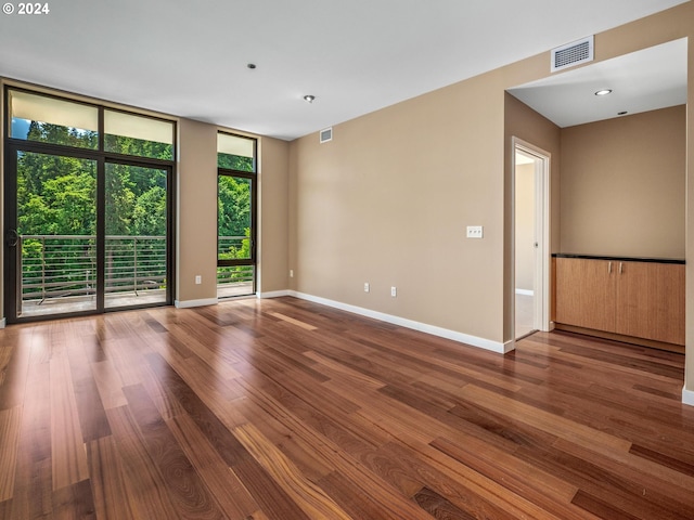 unfurnished room featuring wood-type flooring and a wall of windows