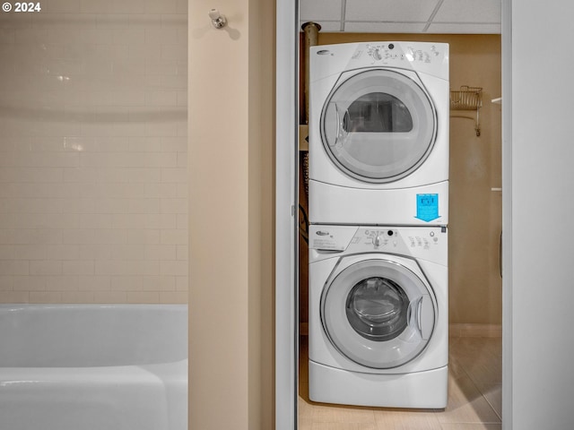 washroom with stacked washer / drying machine and light tile patterned flooring