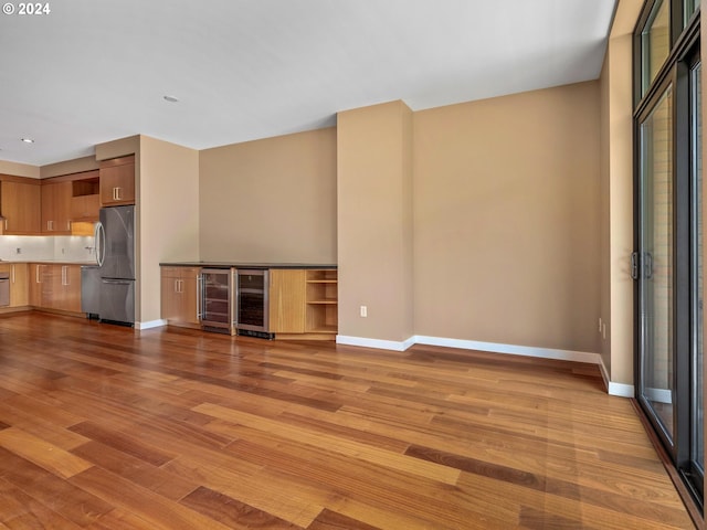 unfurnished living room featuring light hardwood / wood-style floors and beverage cooler