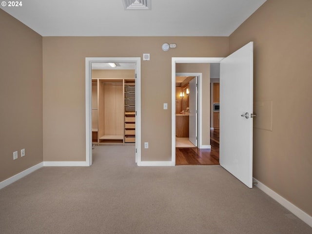 unfurnished bedroom featuring a closet, carpet floors, and a walk in closet