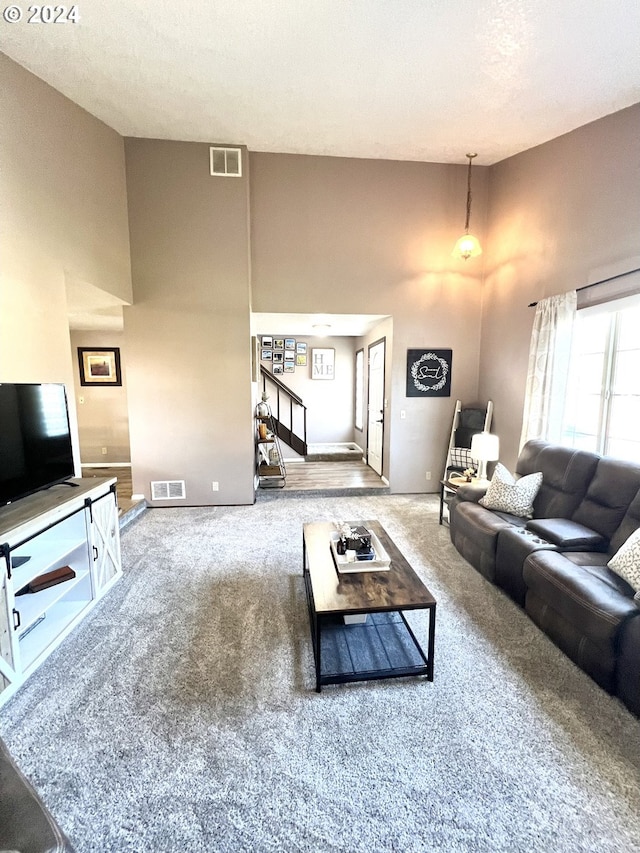 living room featuring a towering ceiling, carpet, and a textured ceiling