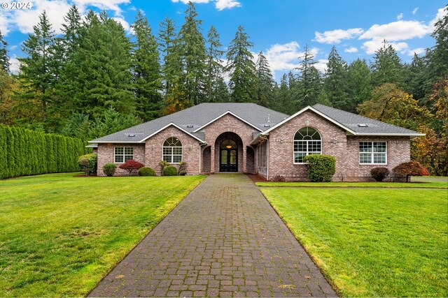 view of front facade featuring aphalt driveway, brick siding, a front lawn, and roof with shingles