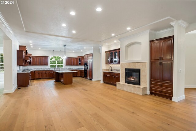 kitchen with a tiled fireplace, recessed lighting, light wood-style floors, and a center island