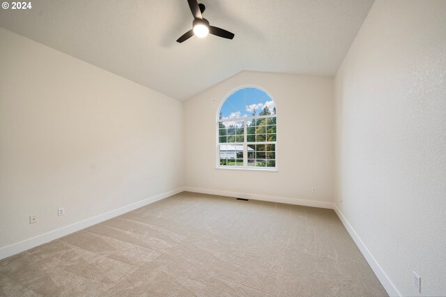 unfurnished room featuring baseboards, visible vents, ceiling fan, vaulted ceiling, and light carpet