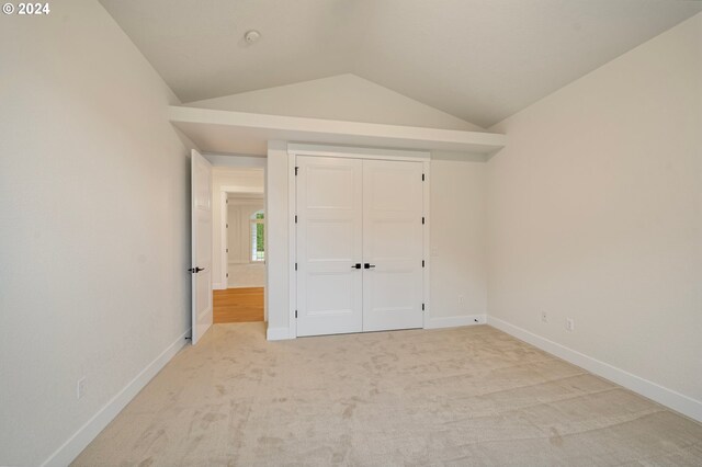 unfurnished bedroom featuring vaulted ceiling, carpet, baseboards, and a closet