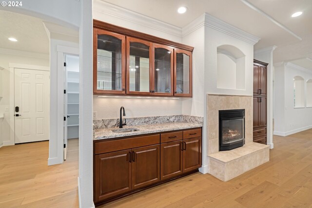 bar featuring ornamental molding, recessed lighting, a tile fireplace, light wood-style floors, and a sink