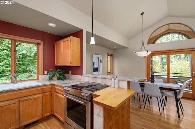 kitchen with kitchen peninsula, stainless steel electric range, light wood-type flooring, and vaulted ceiling