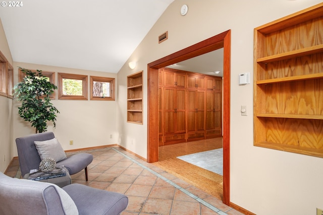 living area featuring lofted ceiling, built in features, and light tile patterned floors