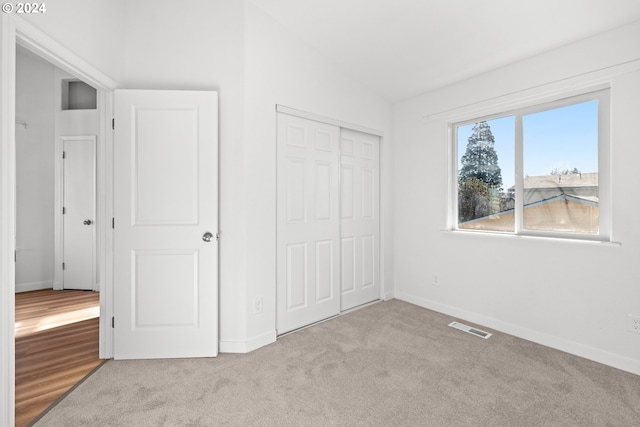 unfurnished bedroom with a closet, light colored carpet, and vaulted ceiling