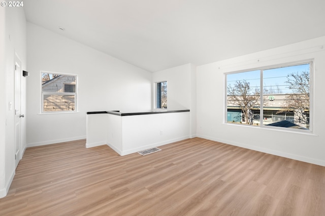 spare room featuring lofted ceiling and light wood-type flooring