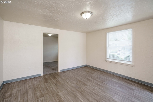 unfurnished room featuring a textured ceiling and dark hardwood / wood-style floors