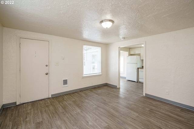 empty room featuring dark wood-type flooring and a textured ceiling