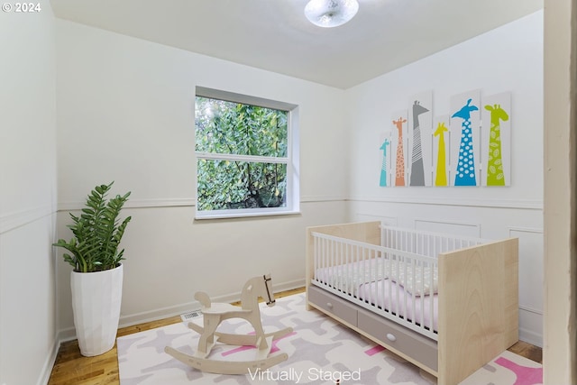 bedroom with hardwood / wood-style floors and a crib