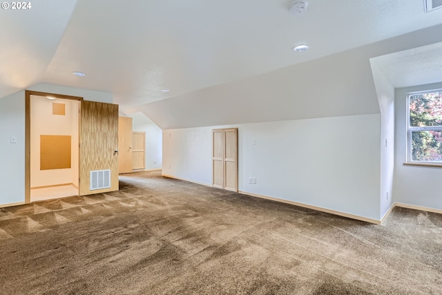 additional living space featuring carpet flooring and vaulted ceiling