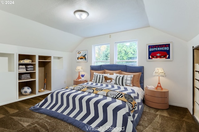 bedroom with lofted ceiling, a textured ceiling, and dark carpet