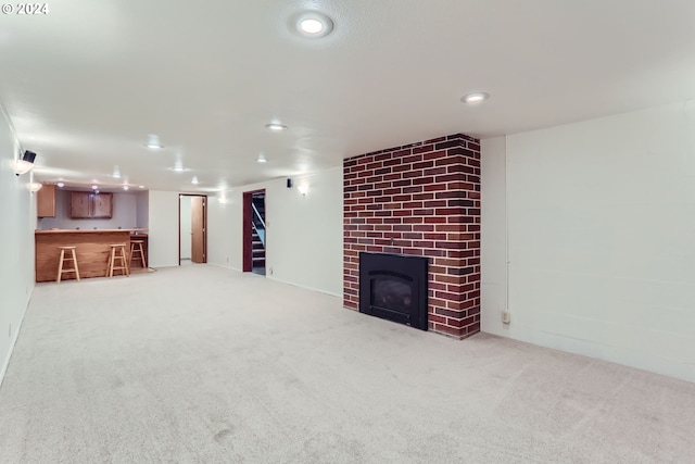 unfurnished living room with a brick fireplace, carpet flooring, and bar area