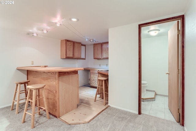 kitchen with a breakfast bar, light colored carpet, and kitchen peninsula