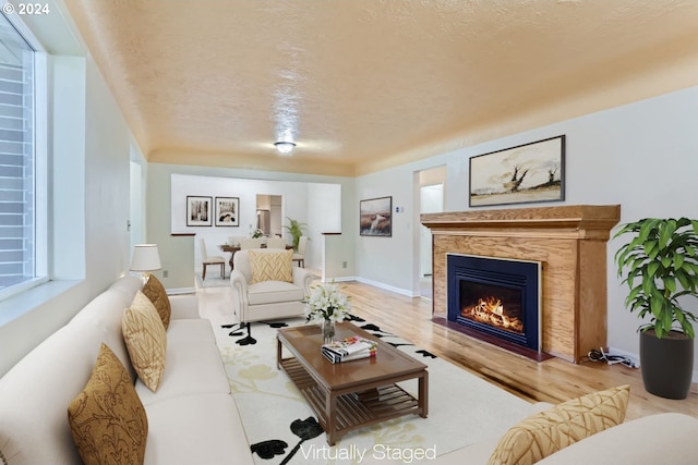 living room featuring a textured ceiling, light wood-type flooring, and a fireplace