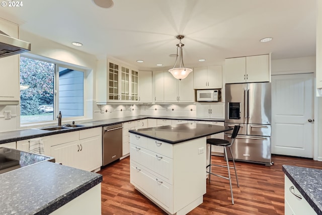 kitchen with appliances with stainless steel finishes, a center island, pendant lighting, white cabinets, and dark hardwood / wood-style floors