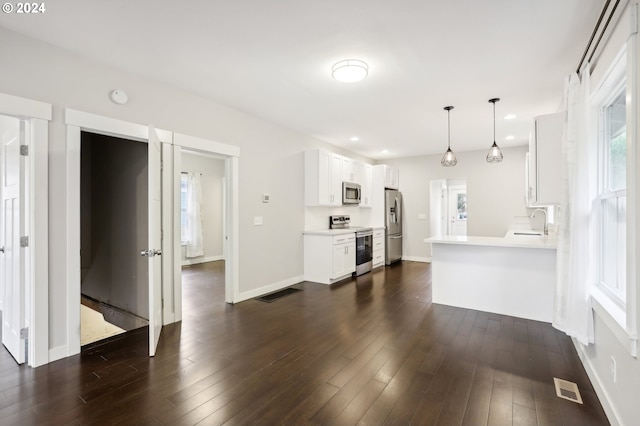 kitchen featuring white cabinets, dark hardwood / wood-style floors, decorative light fixtures, and appliances with stainless steel finishes