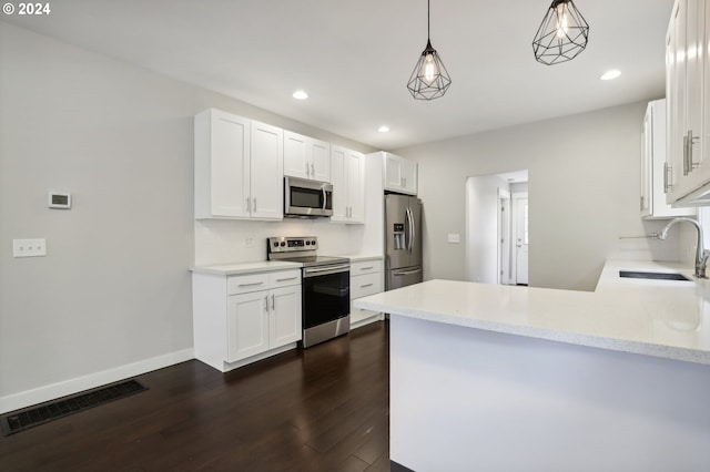 kitchen featuring white cabinets, hanging light fixtures, dark hardwood / wood-style flooring, kitchen peninsula, and stainless steel appliances