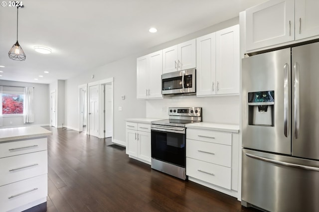 kitchen with white cabinets, appliances with stainless steel finishes, decorative light fixtures, and dark wood-type flooring