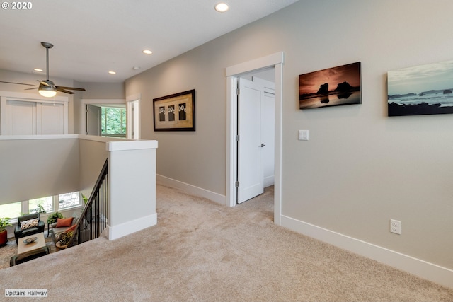hall featuring an upstairs landing, light carpet, recessed lighting, and baseboards