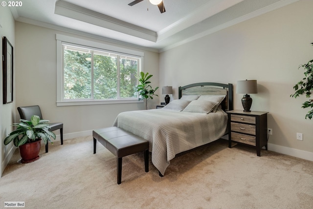 bedroom featuring crown molding, light colored carpet, a tray ceiling, baseboards, and a ceiling fan