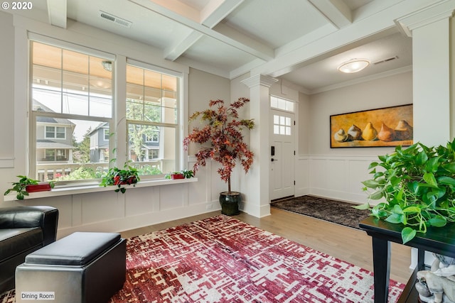 entrance foyer featuring wood finished floors, a decorative wall, beam ceiling, decorative columns, and wainscoting
