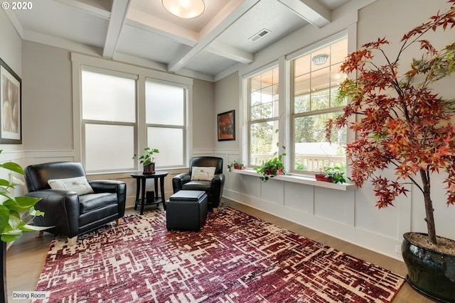 sitting room featuring a decorative wall, coffered ceiling, wood finished floors, beam ceiling, and a wainscoted wall
