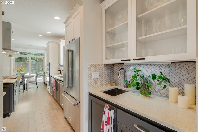 kitchen featuring a sink, stainless steel appliances, decorative backsplash, light stone counters, and recessed lighting