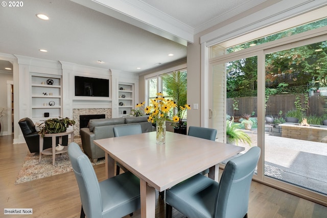 dining area with ornamental molding, wood finished floors, a fireplace, recessed lighting, and built in features