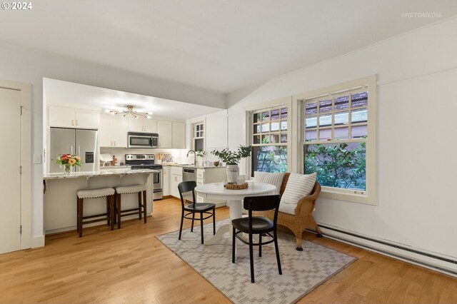 dining space featuring light hardwood / wood-style flooring, sink, and a baseboard radiator