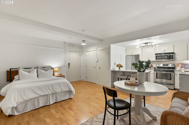 bedroom with two closets, built in refrigerator, and light hardwood / wood-style flooring