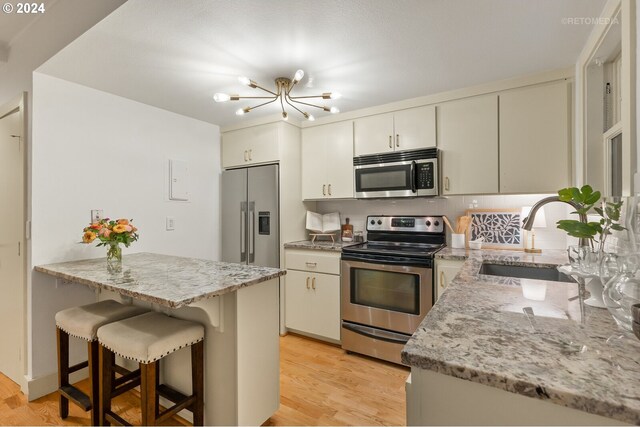 kitchen featuring a kitchen bar, sink, appliances with stainless steel finishes, and light hardwood / wood-style floors