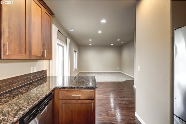 kitchen with dark wood-type flooring, dark stone counters, and appliances with stainless steel finishes