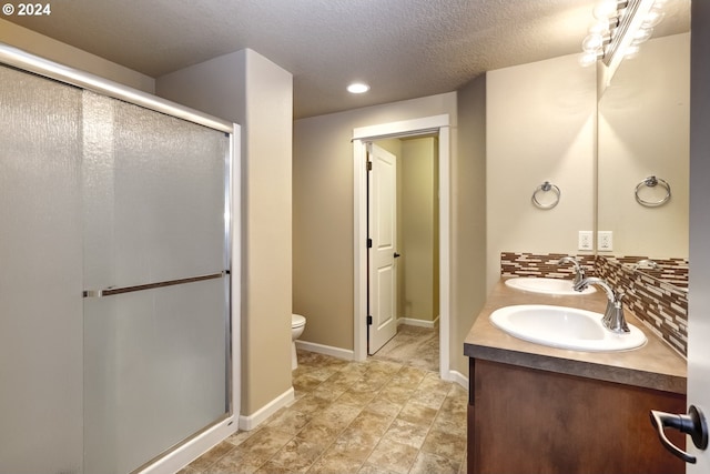 bathroom featuring tasteful backsplash, vanity, a shower with shower door, and toilet