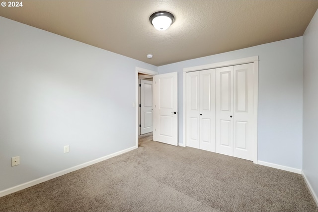 unfurnished bedroom with light carpet, a closet, and a textured ceiling