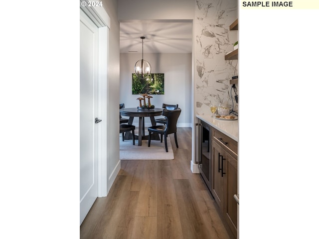 kitchen featuring an inviting chandelier, light hardwood / wood-style flooring, hanging light fixtures, and beverage cooler