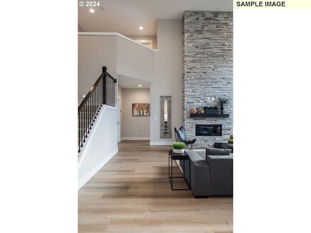 living room with light hardwood / wood-style floors, a towering ceiling, and a fireplace