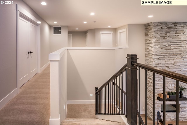 stairway featuring light colored carpet