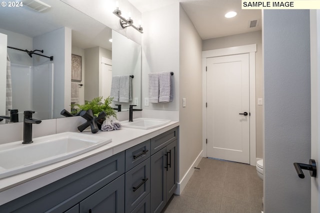 bathroom featuring double vanity, toilet, and tile floors